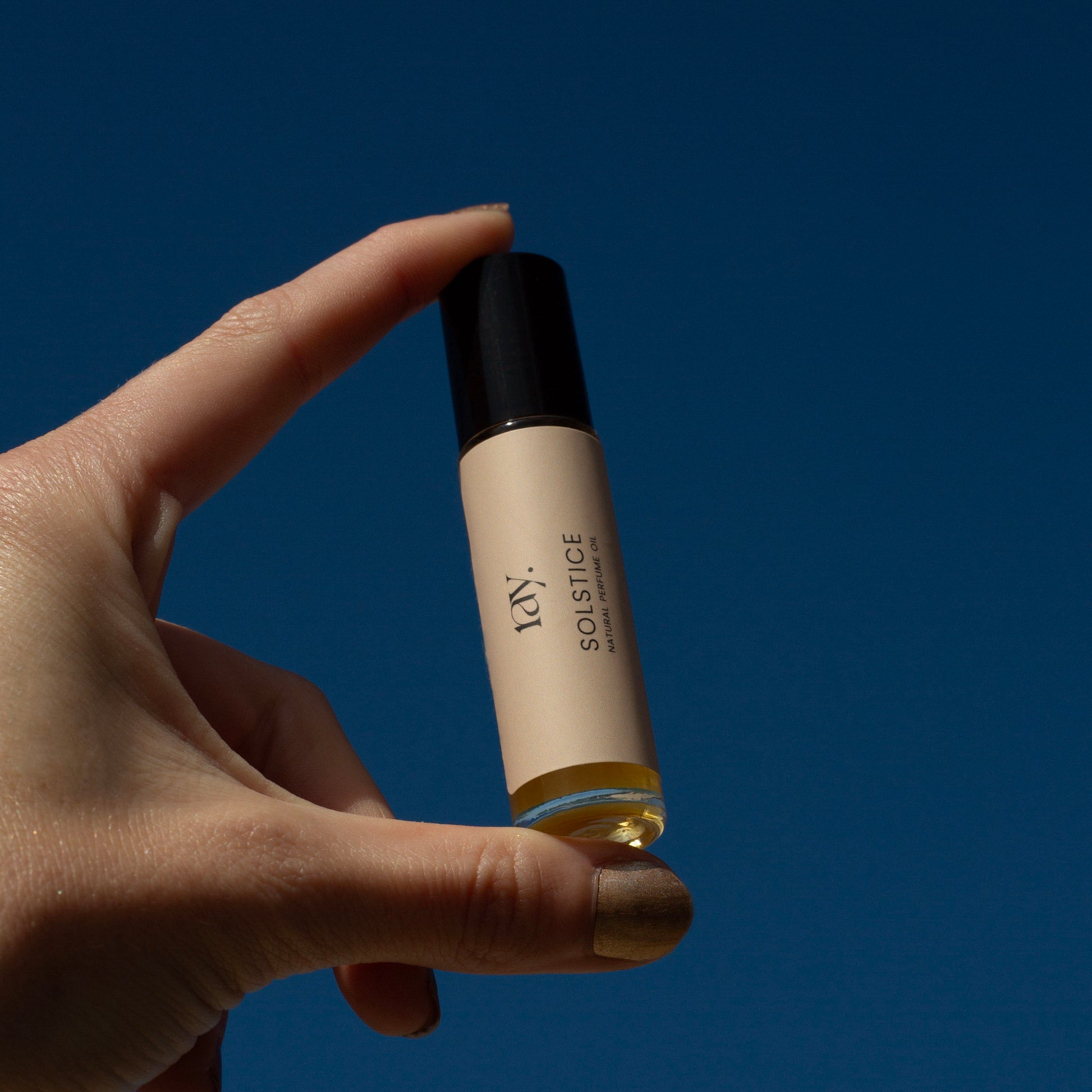 Woman holding travel size natural perfume oil up to the sky